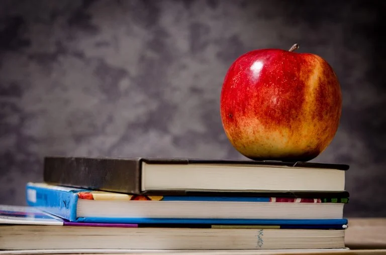a red apple on top of a stack of books