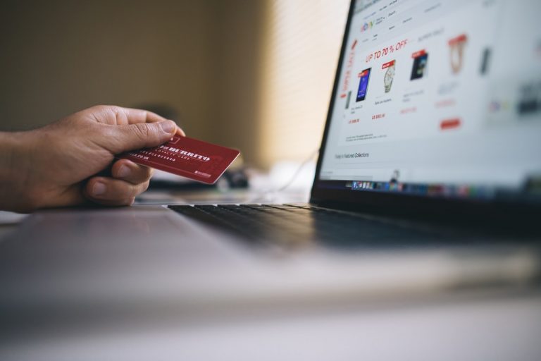 a hand holding a red card in front of a laptop