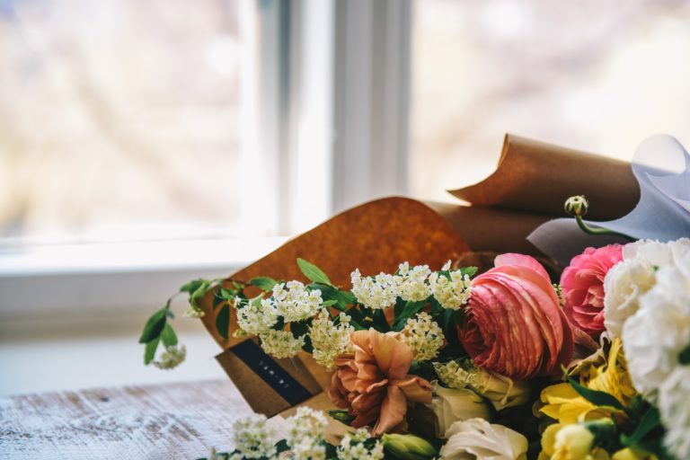 a hand holding a knife over a bouquet of flowers