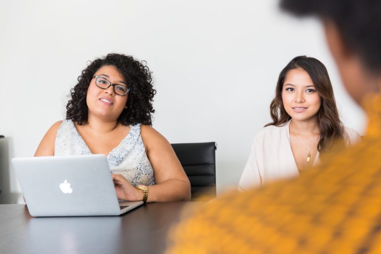 a group of women sitting at a table with a laptop