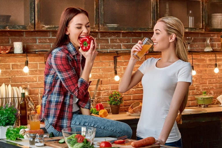 a couple of women eating in a kitchen